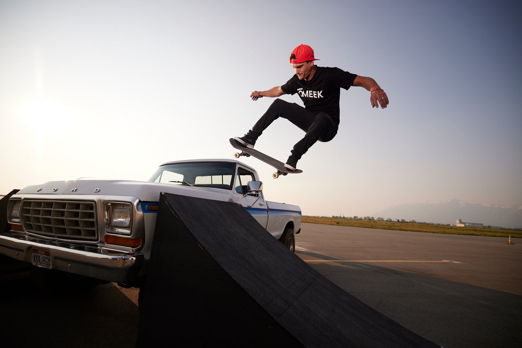 Kam Atwood in a red cap skating a ramp in front of a truck.