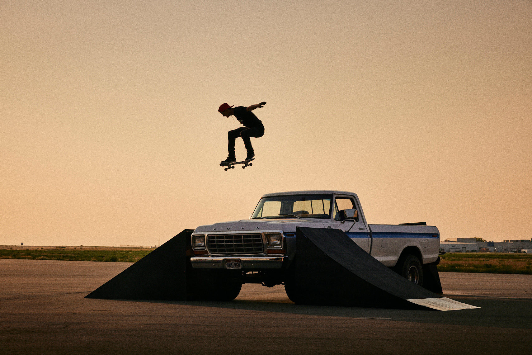Kam Atwood jumping a skateboard over a truck bed.