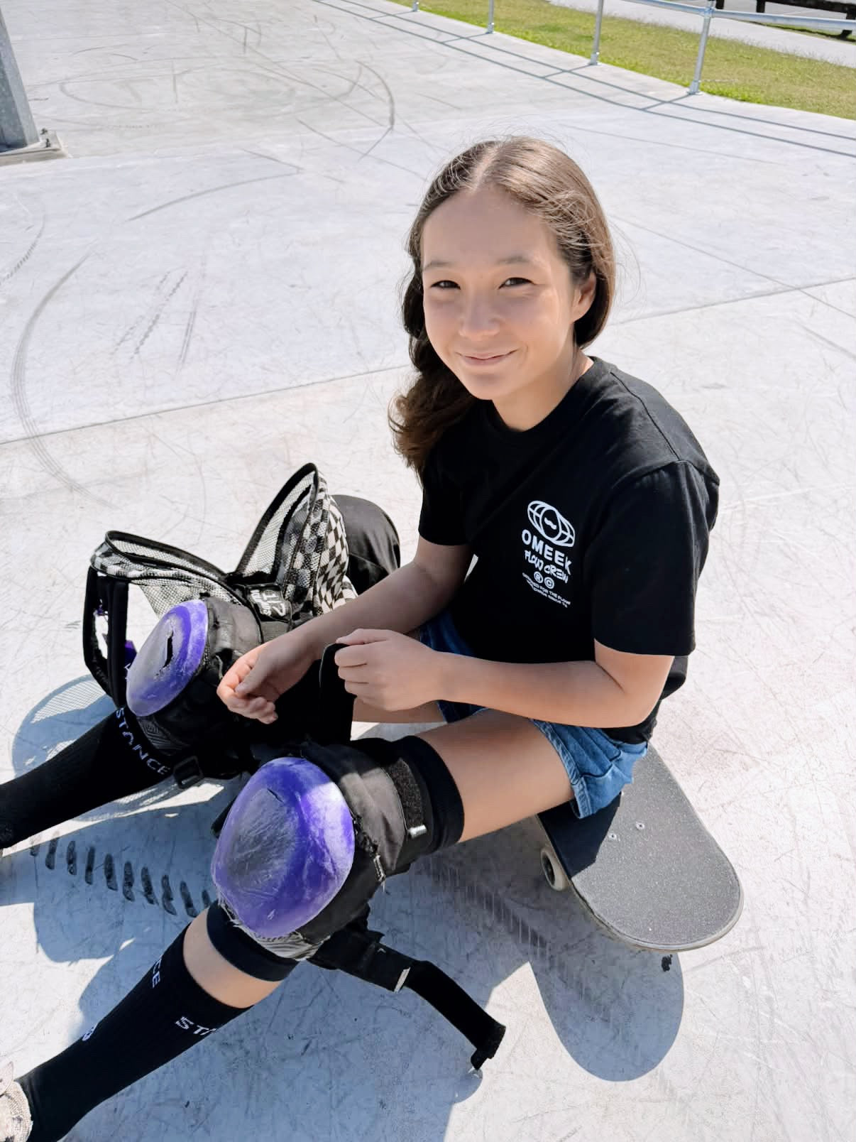 Ivy Raftery sitting on a skateboard wearing protective gear.