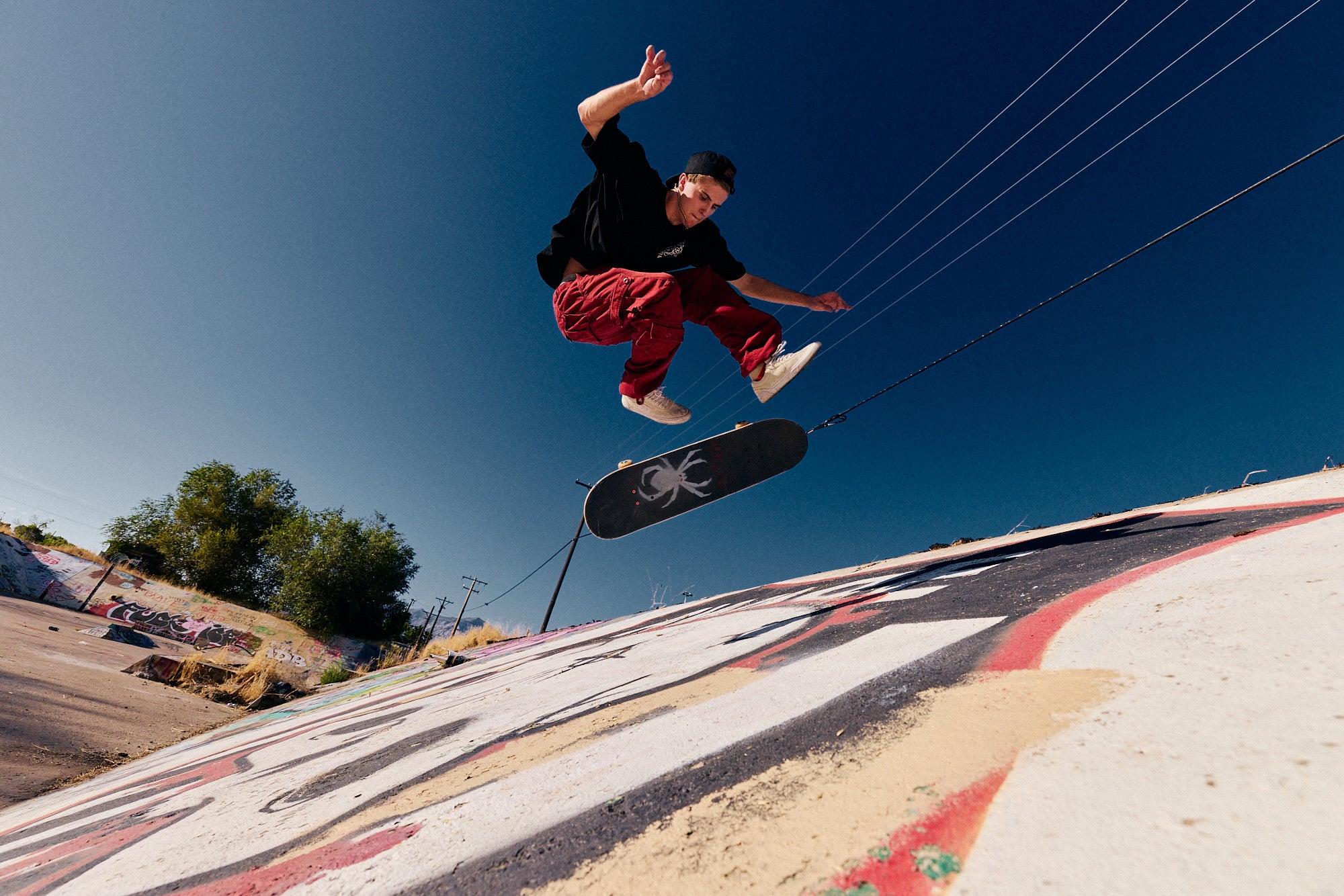 Parker DeMoux ollieing a skateboard above a painted ramp.