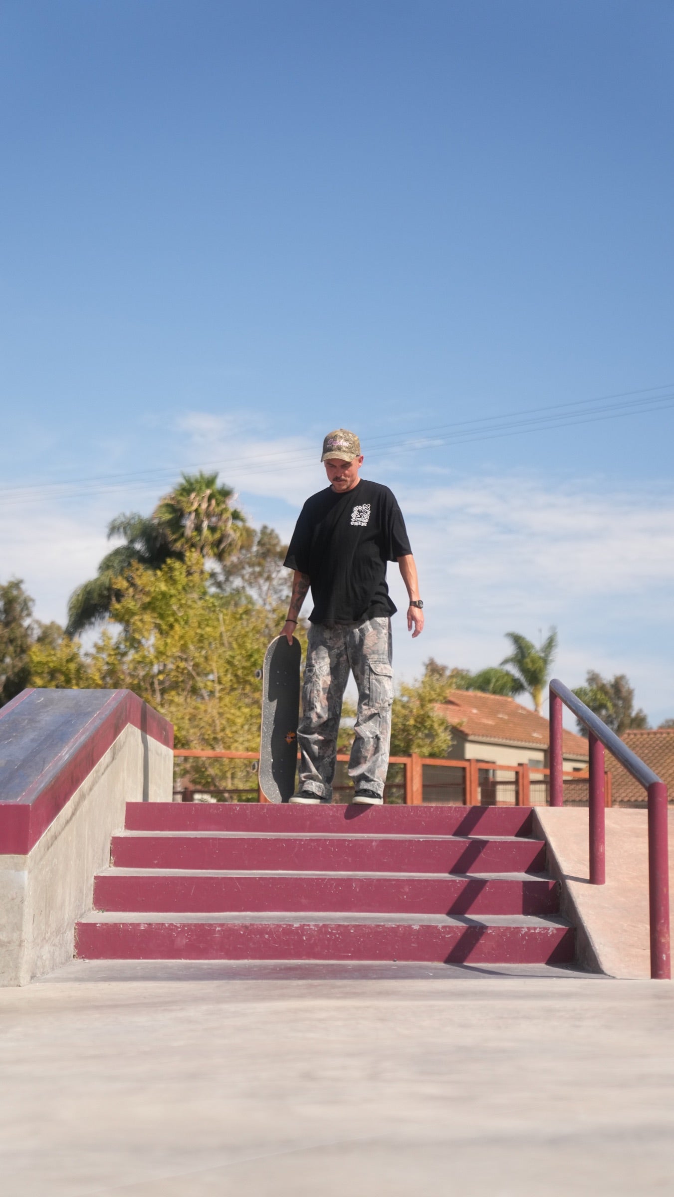 Phil Ceja standing with a skateboard at the top of a stair set.