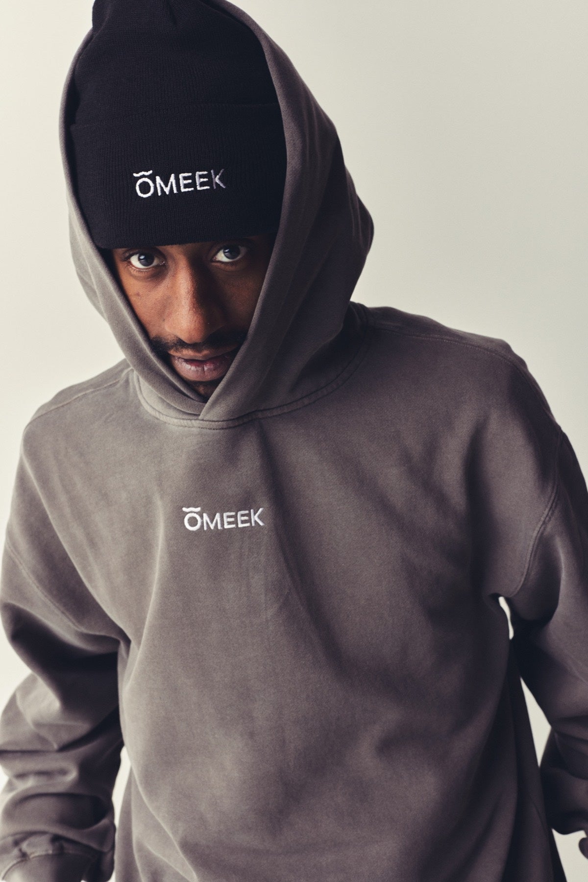 Man in a gray OMEEK hoodie and beanie.